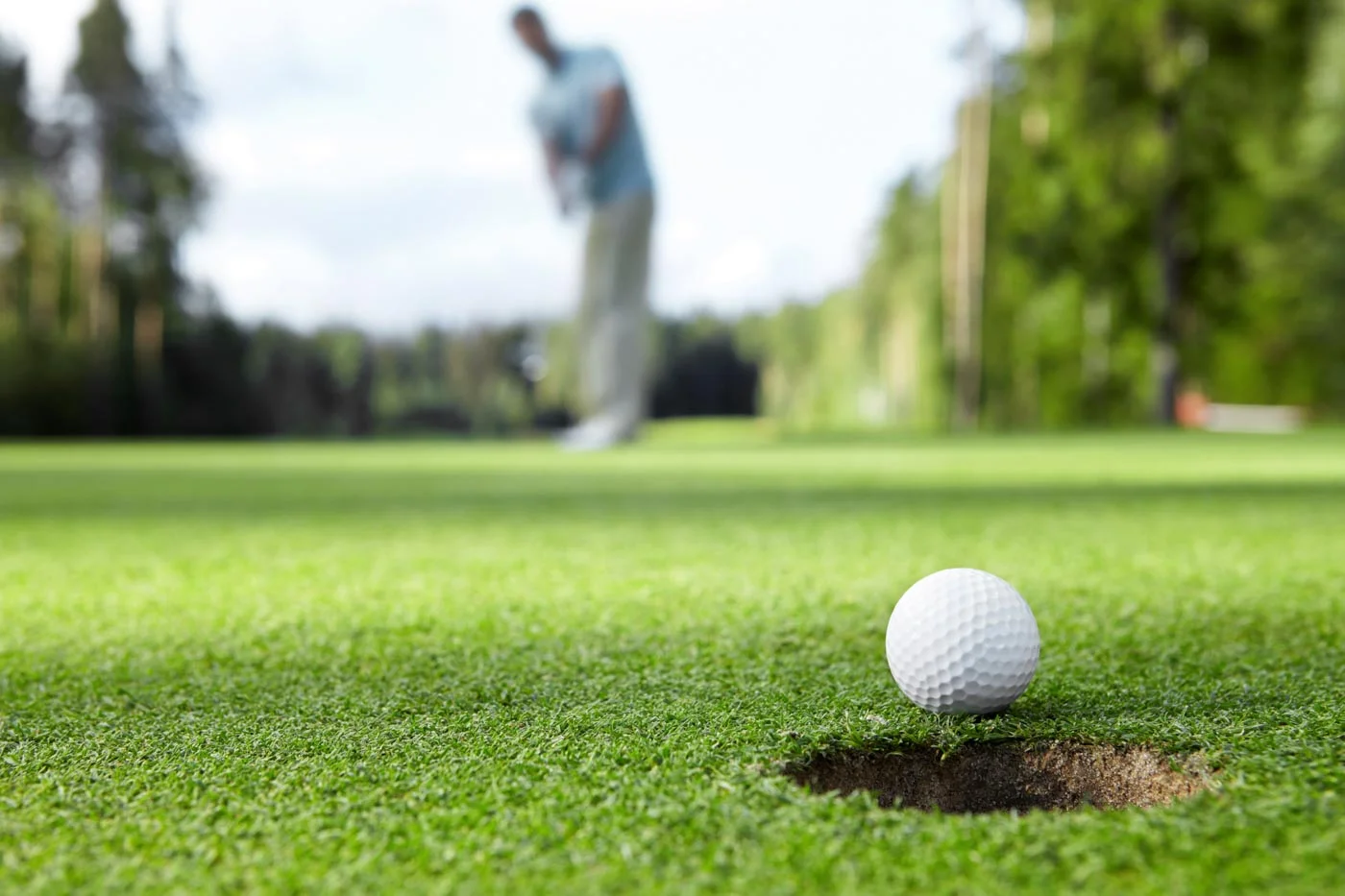 golfer putting a golf ball into the hole