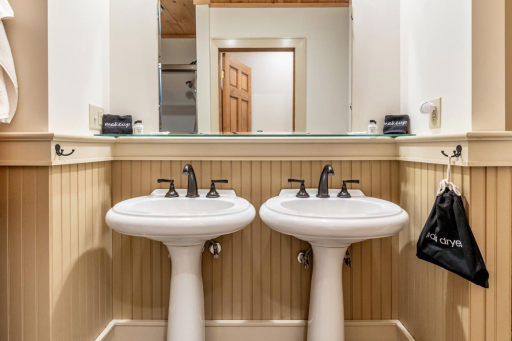 a couple of white sinks sitting under a bathroom mirror
