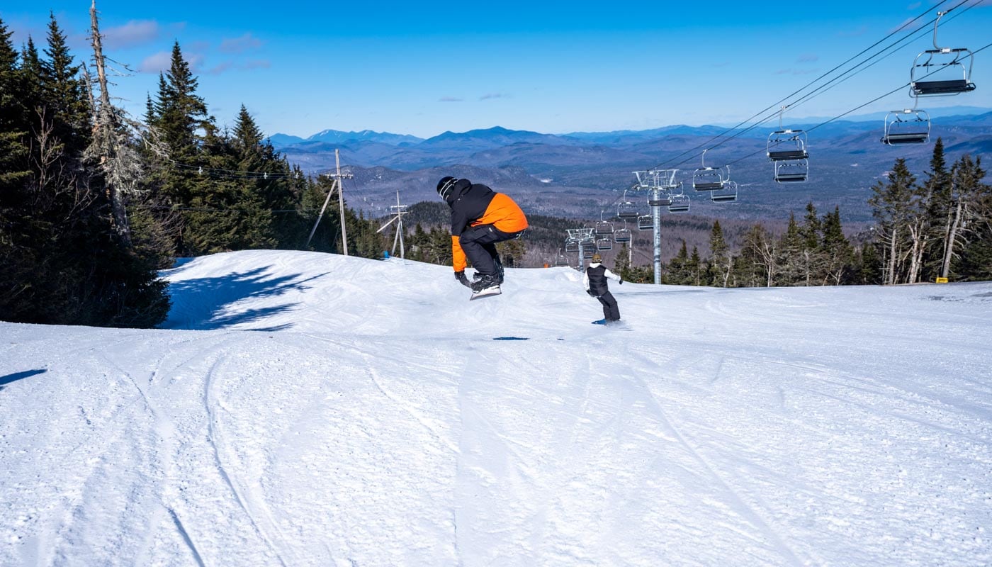 a man riding a snowboard down the side of a snow covered slope