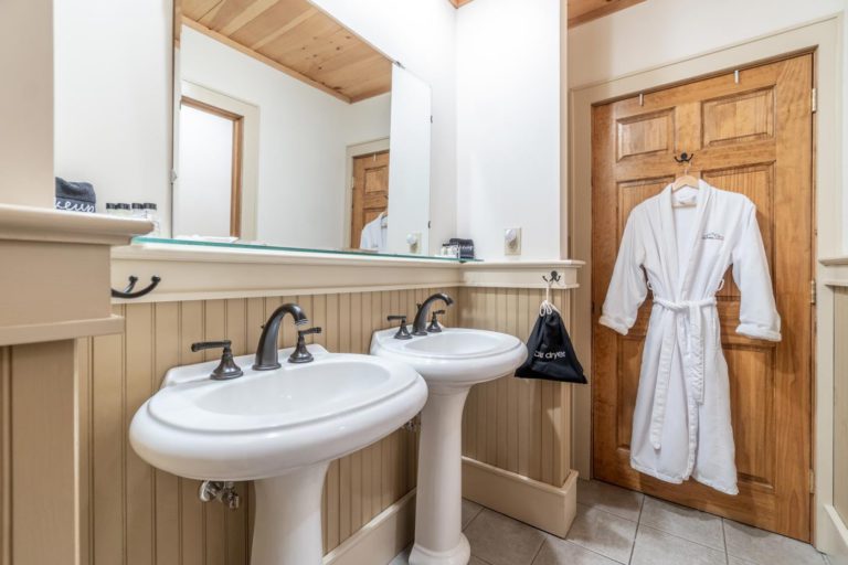 a bathroom with two sinks and a robe hanging on the door