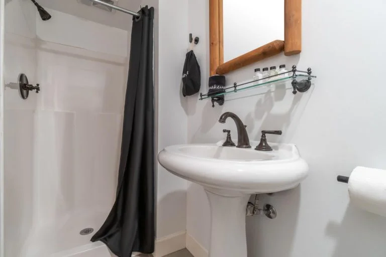 a bathroom with a sink, mirror, and shower