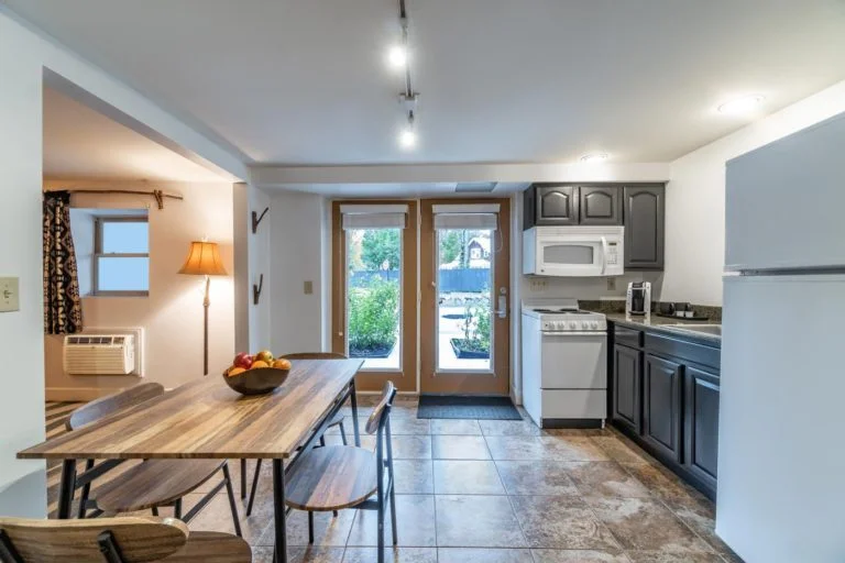 a kitchen area with a table, refrigerator, microwave and a door