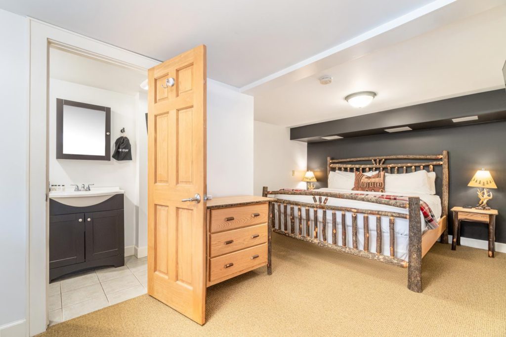 a hotel room with a bed, dresser and mirror