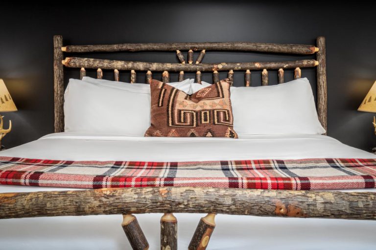 a bed with a wooden head board and a plaid blanket