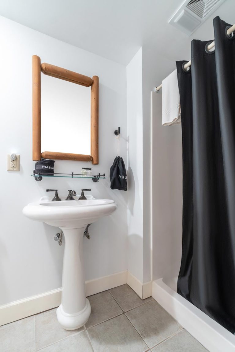 a bathroom with a sink, mirror and shower curtain
