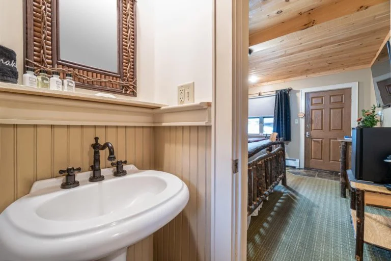 a bathroom with a sink, mirror and television