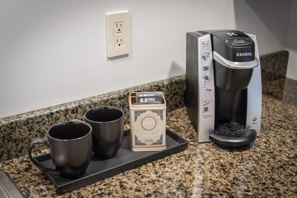 a coffee maker sitting on top of a counter next to two cups