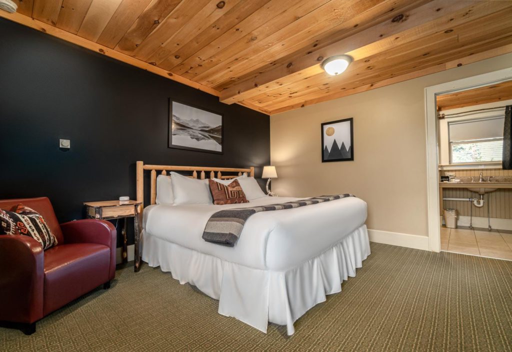 a bed sitting in a hotel room next to a red chair