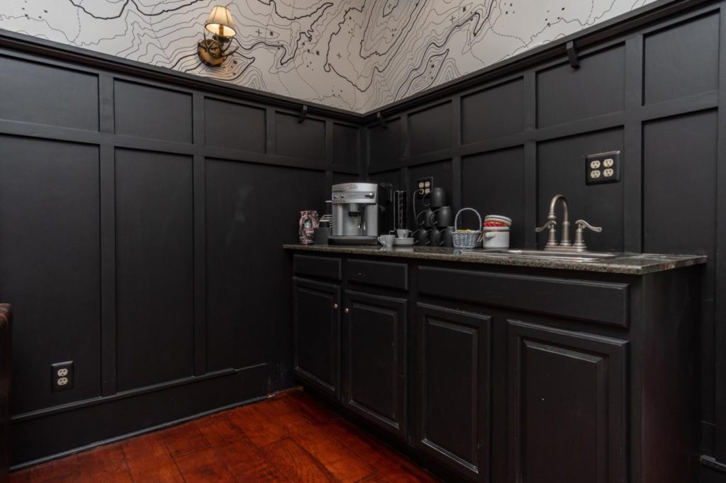 a kitchen with black cabinets and wood floors