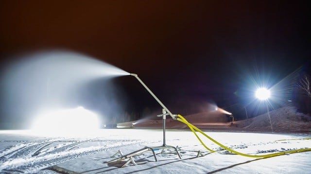 a fire hydrant spewing water on a snow covered field