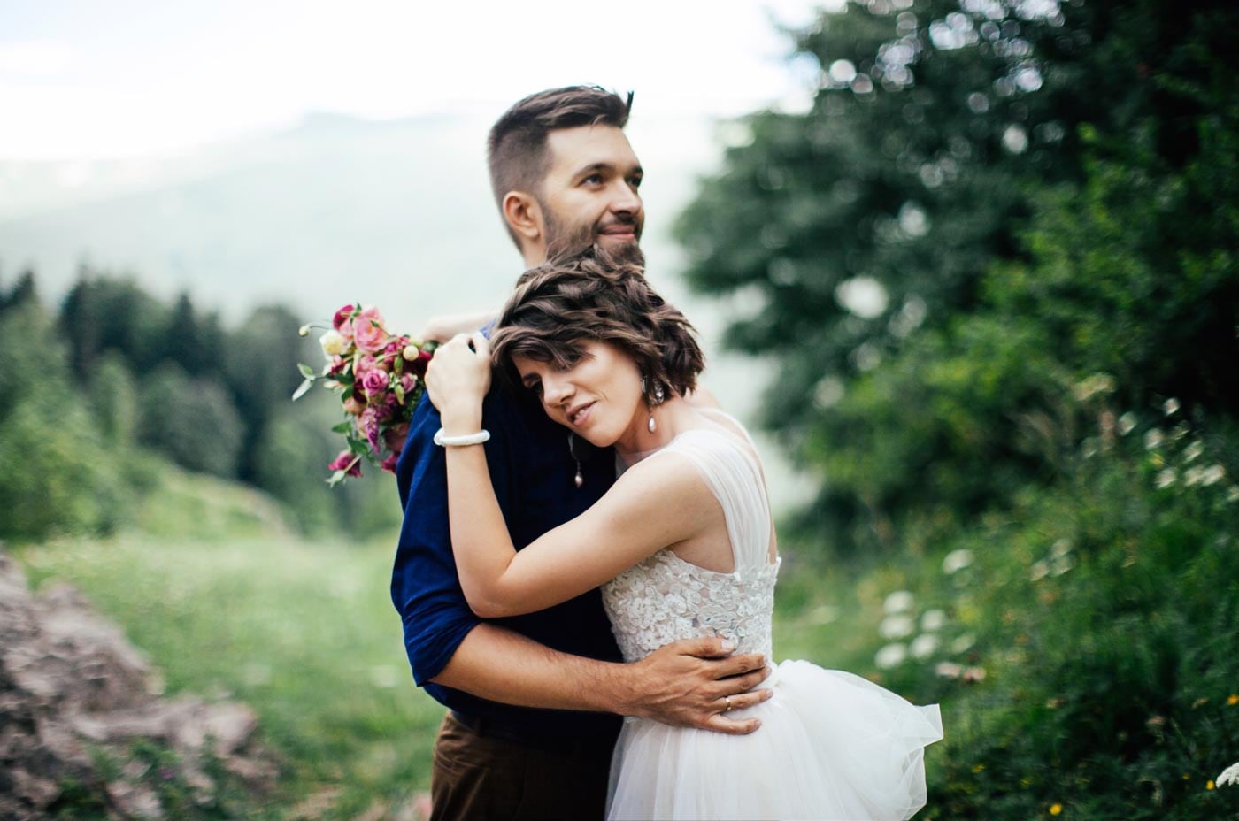 a bride and groom embracing each other in the mountains