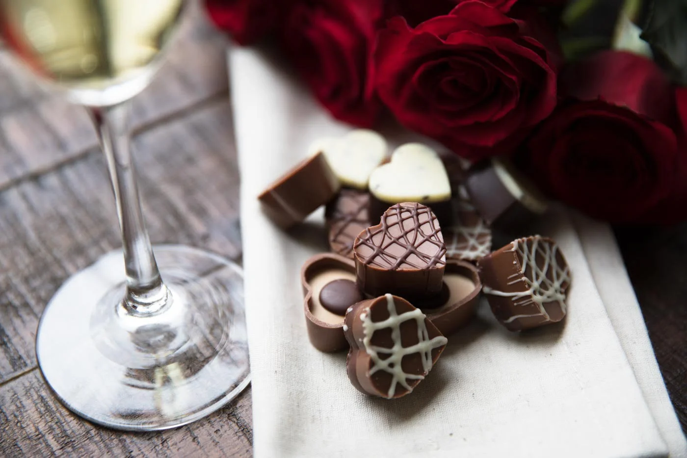 a glass of wine and some chocolates on a table