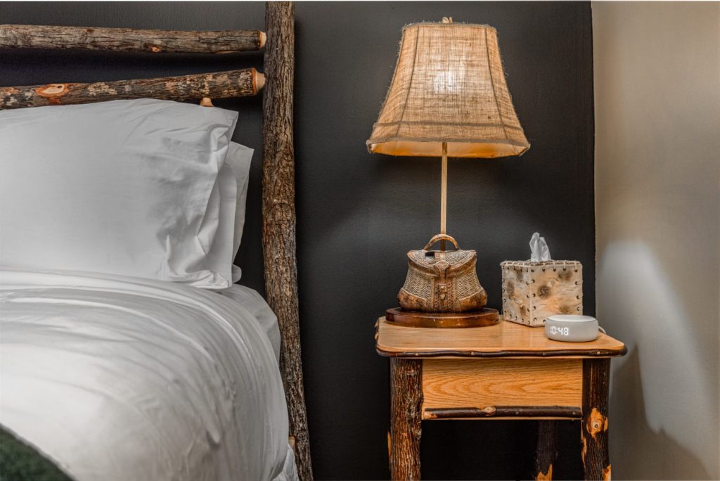 a hotel room with a bed, nightstand and lamp